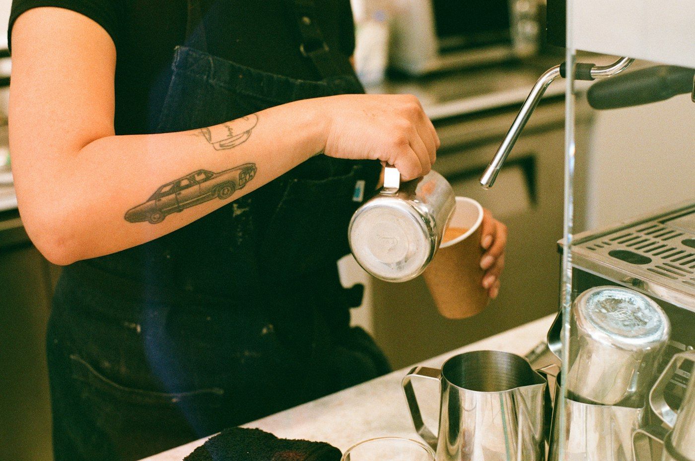 Barista schenkt melk in een kop koffie