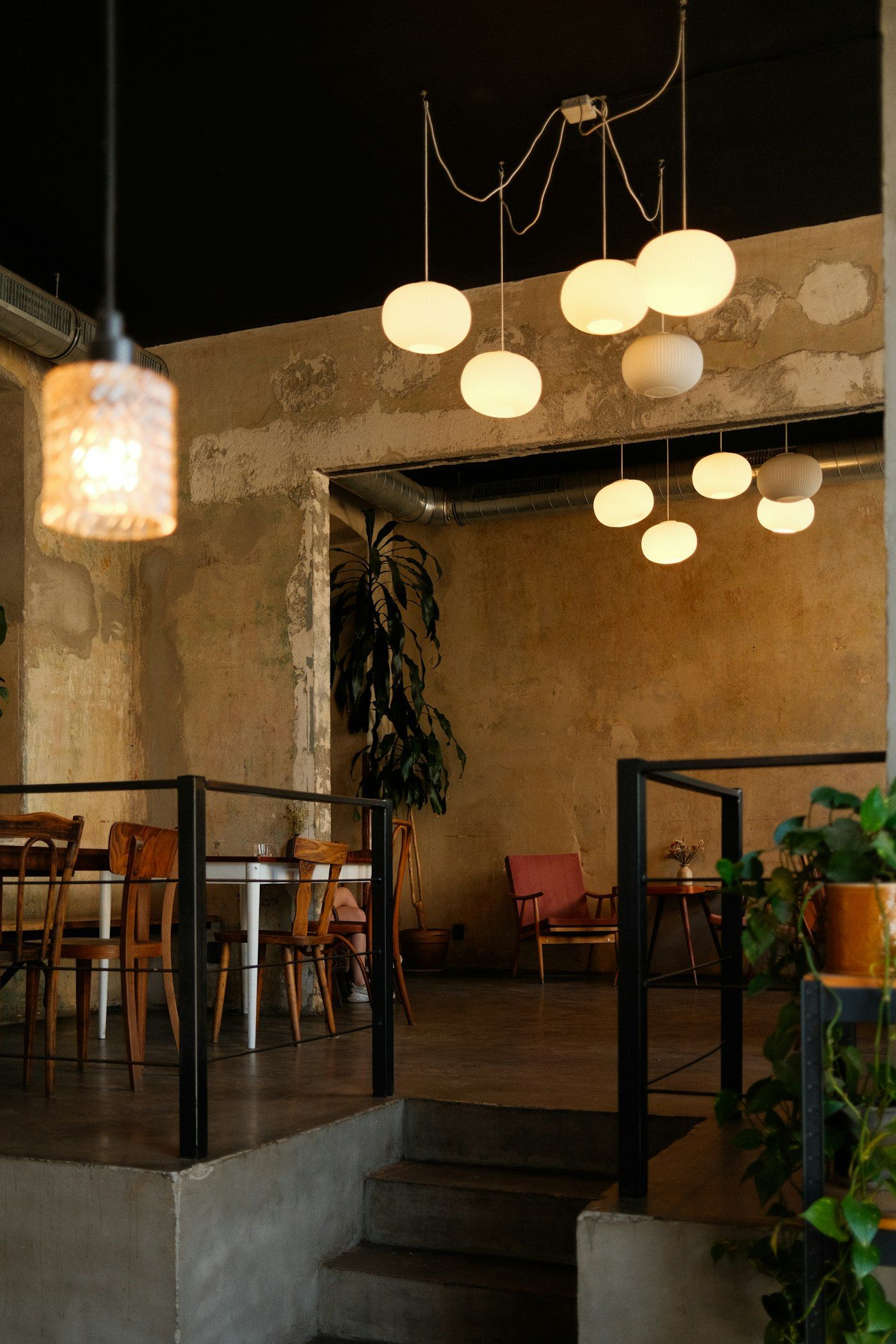 Interieur van het café met hangende bollampen, planten en houten tafels